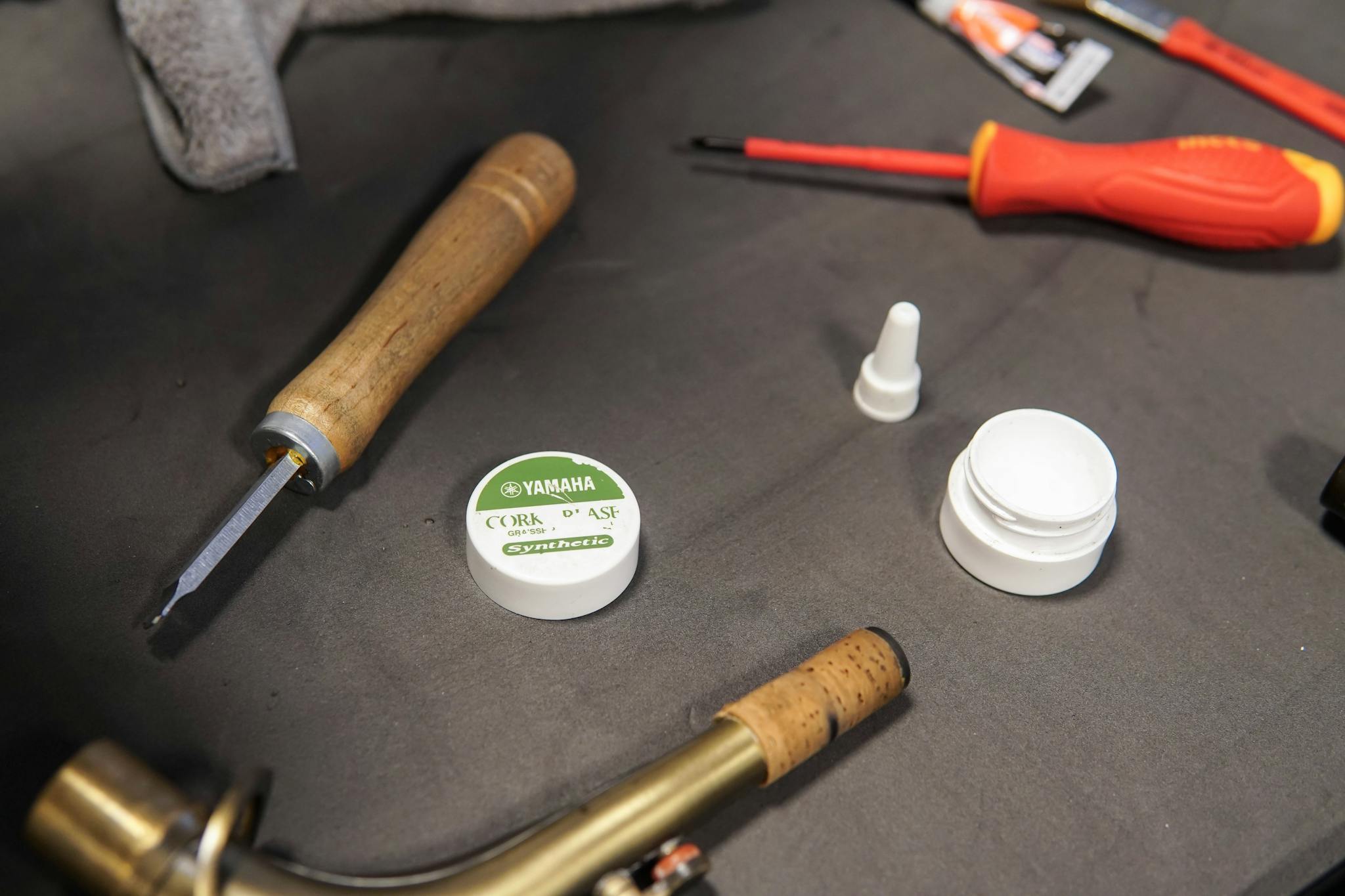 A close-up of tools and glue used in musical instrument repair on a workbench.