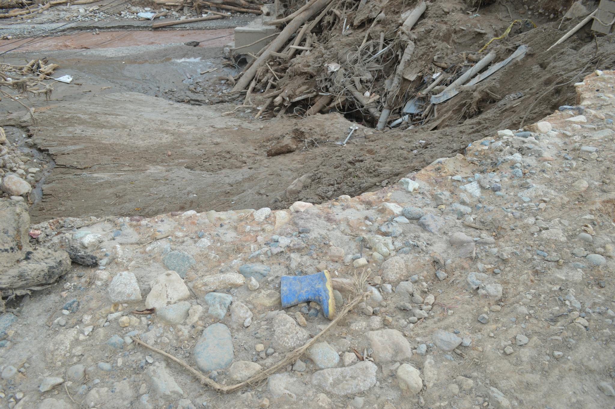 A landscape showing mud, debris, and a lone boot in Mocoa, Colombia's natural disaster aftermath.